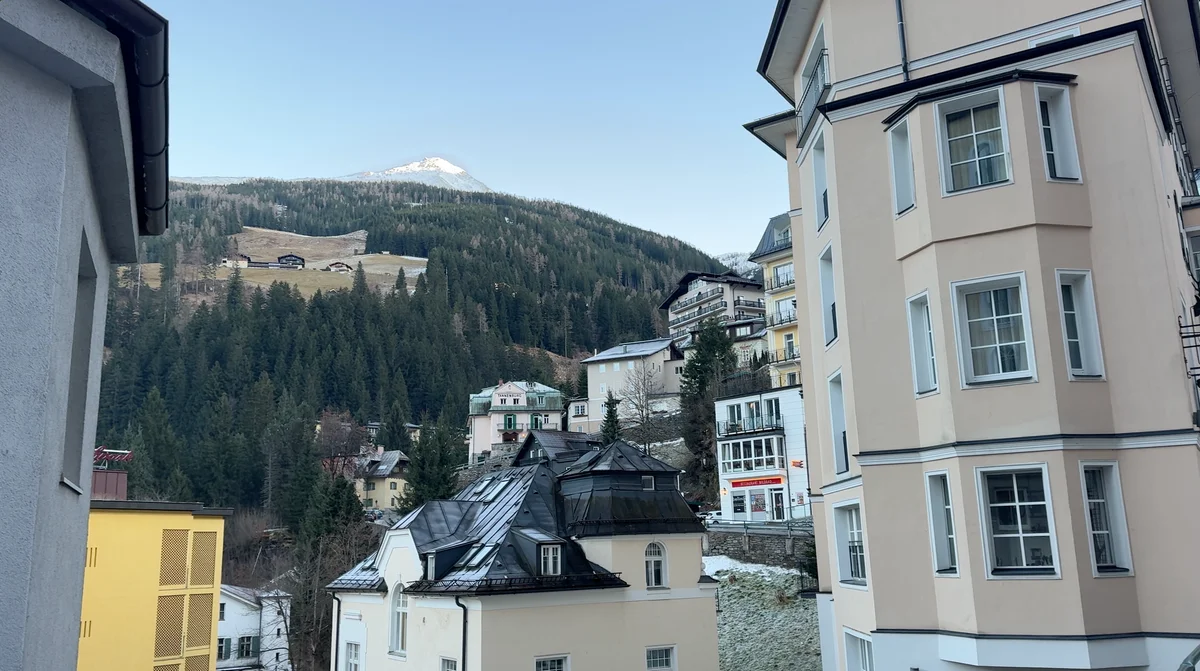 Buildings in Bad Gastein beneath a wooded mountainside and a lightly snow-covered peak.