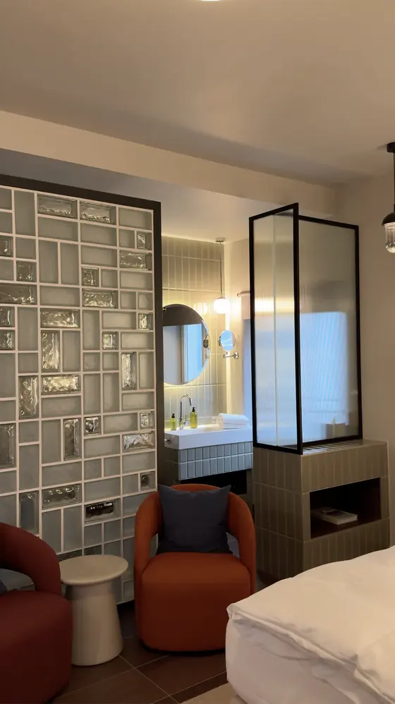 Glass-block partition and orange chairs beside the bathroom basin and frosted-glass screen.