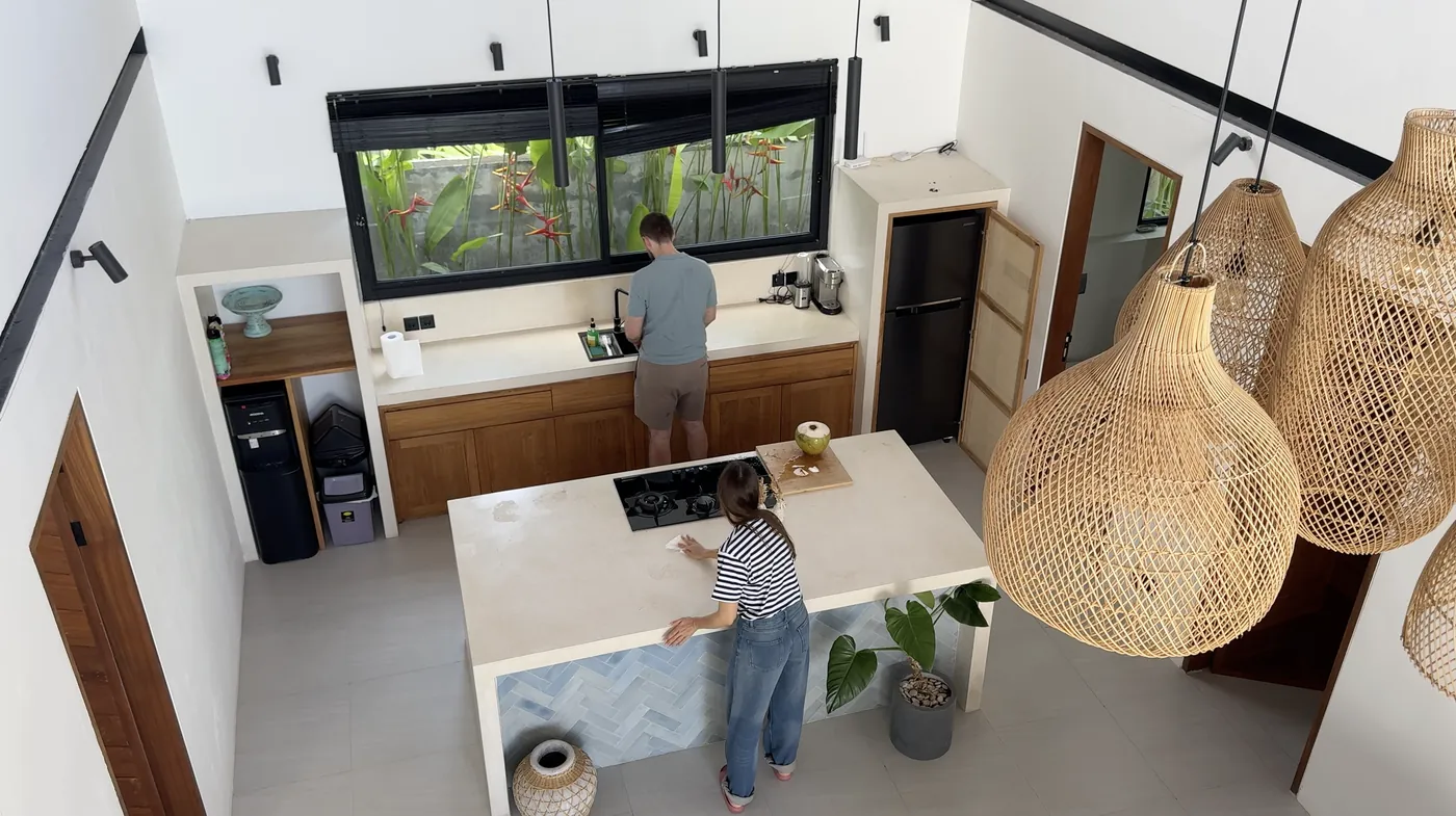 An open kitchen with a stone island and large rattan pendant lamps