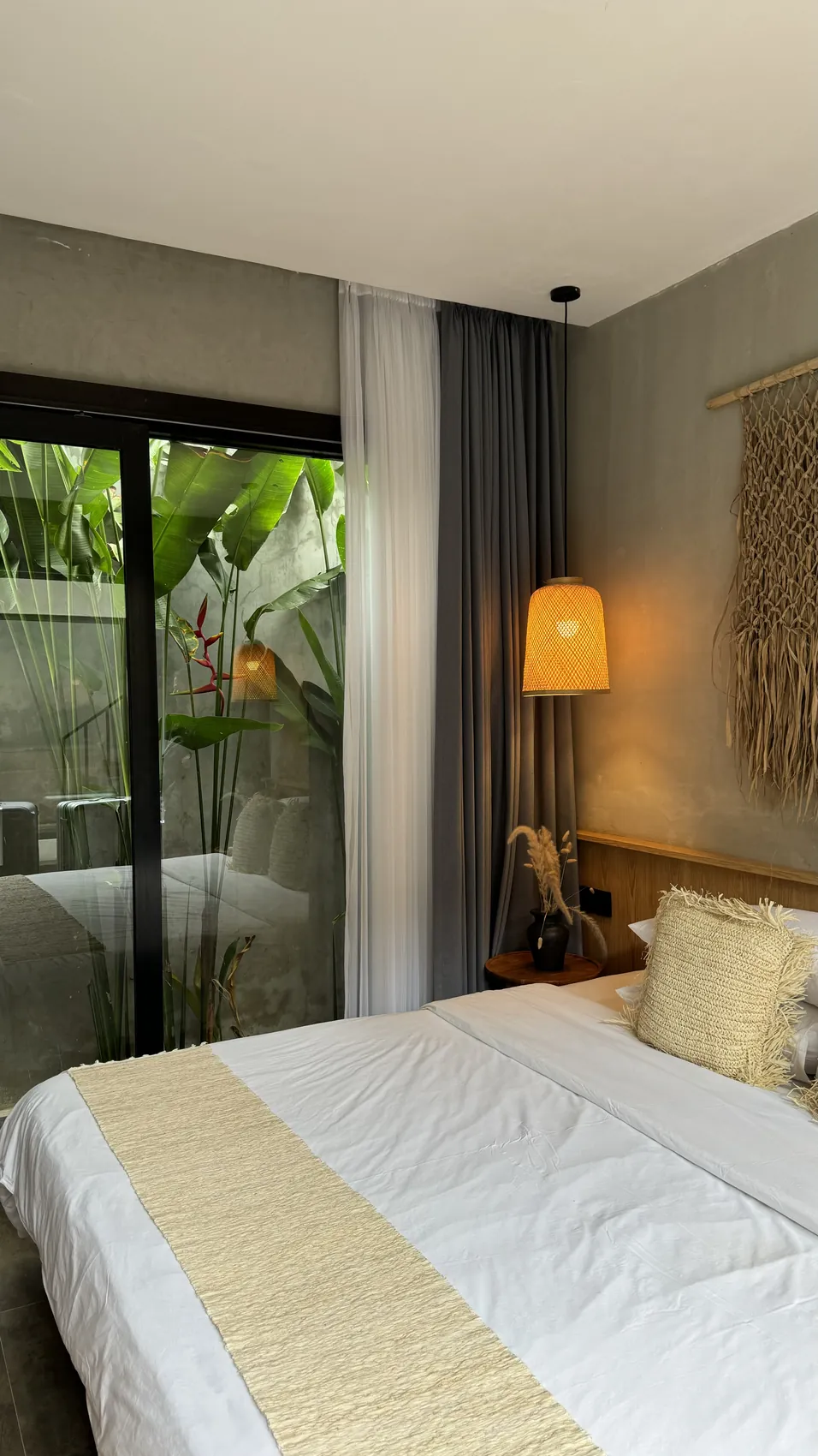 A bedroom with a white bed and a warm lamp next to a glass door