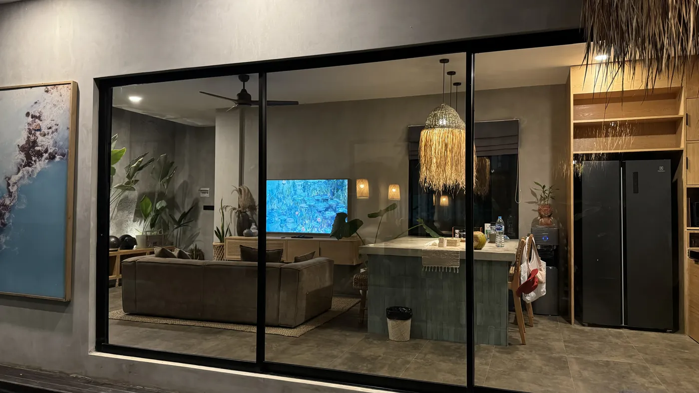 A lit living room seen through large glass doors in the evening