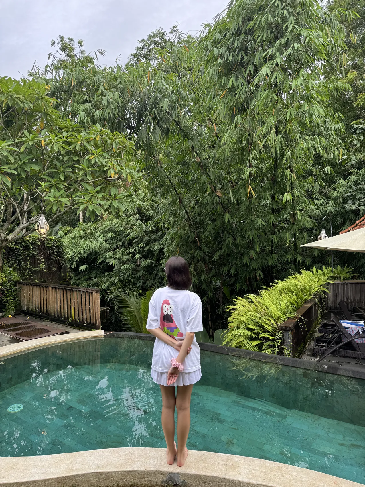 Me standing at the edge of the pool with bamboo behind me