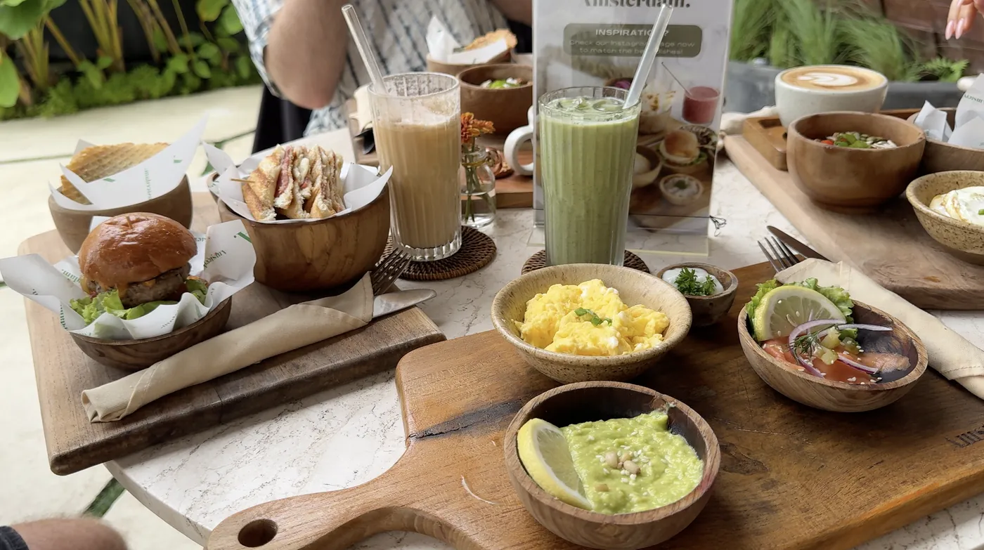 A wooden board with scrambled eggs, guacamole, a burger and sandwiches at Amsterdam