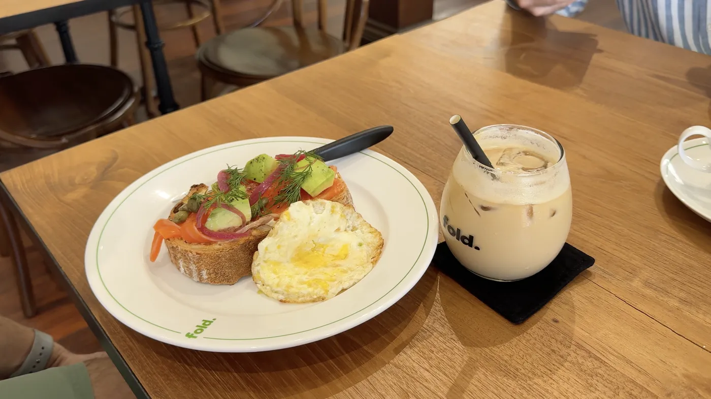 Toast with smoked salmon, avocado and a fried egg next to an iced coffee