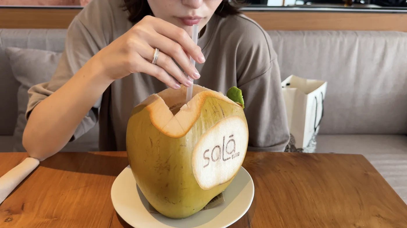 Me drinking from a coconut with a straw at a table in Sala
