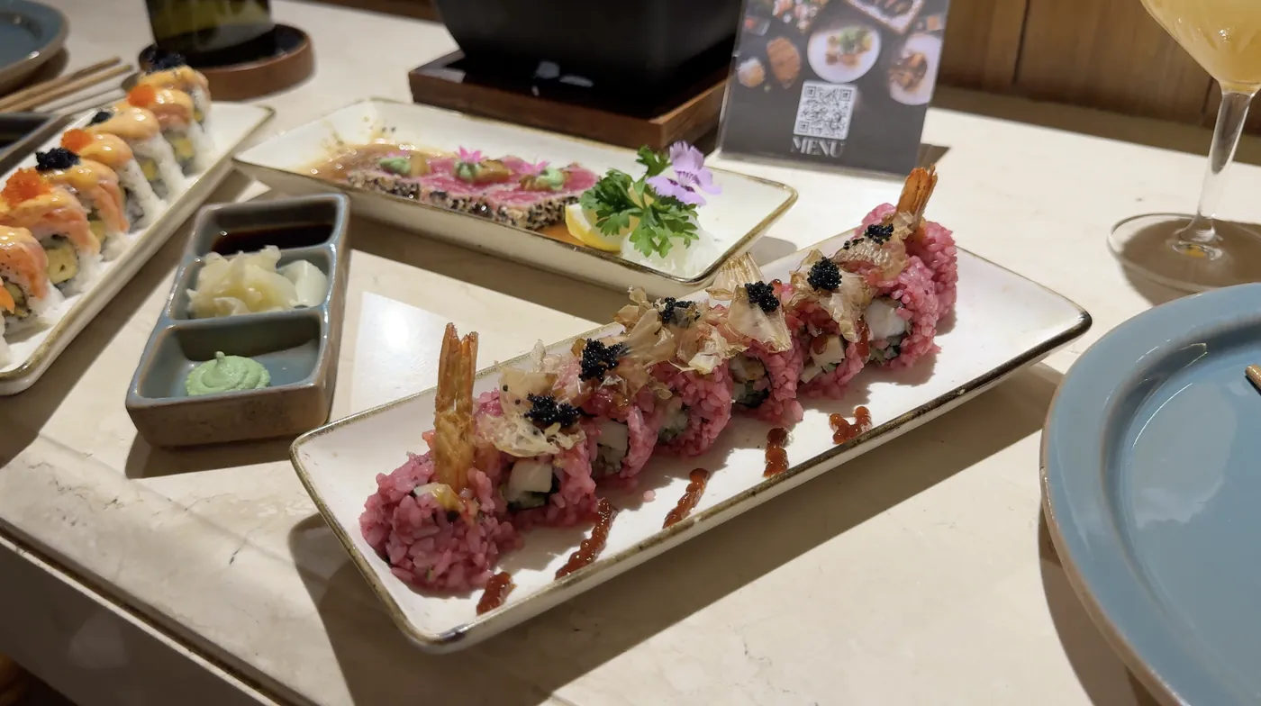Sushi rolls with caviar on long plates next to a cocktail