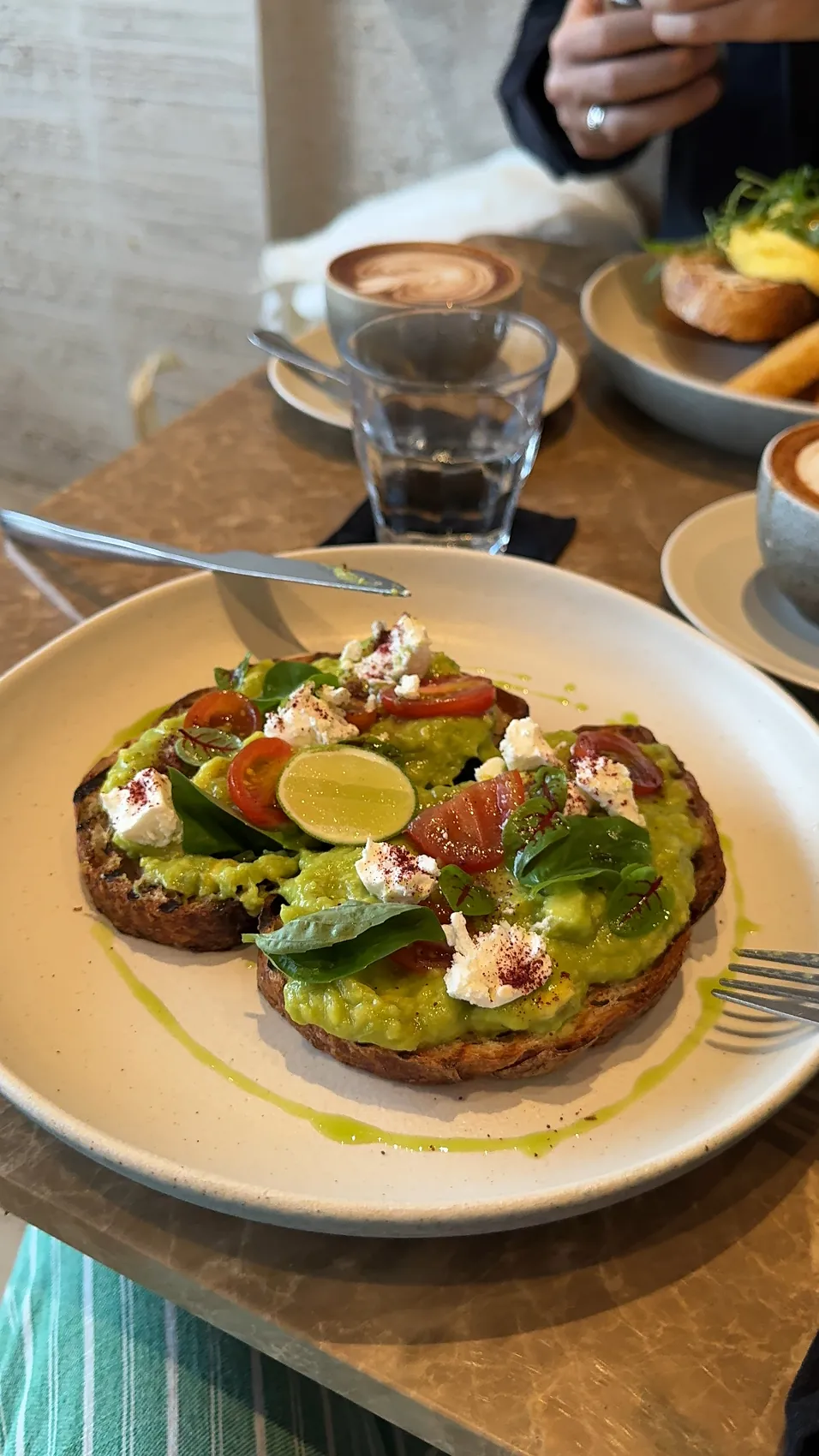 Avocado toast with tomatoes and lime on a large plate
