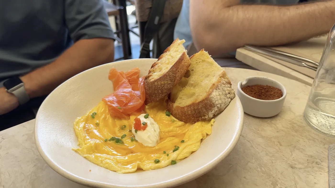 Scrambled eggs with smoked salmon and two slices of bread in a bowl