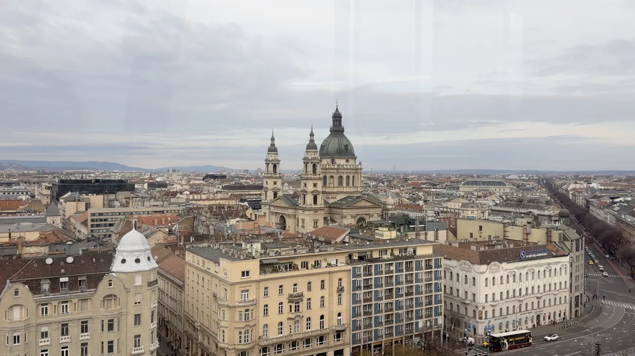 A view over city rooftops with the basilica dome and towers in the distance.