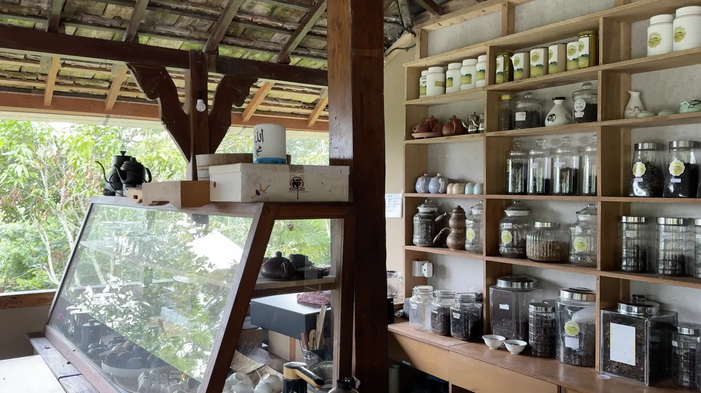 Shelves of tea jars and teaware in an open wooden pavilion