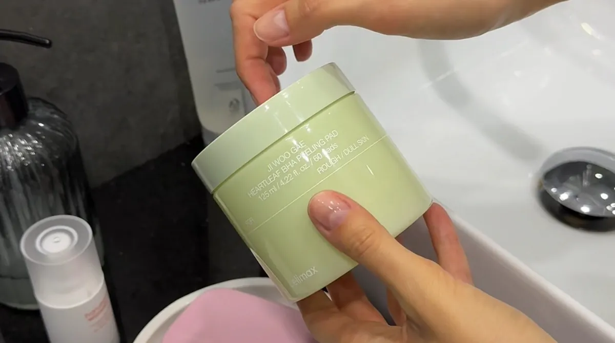 A hand holding a green jar of Celimax Heartleaf BHA exfoliating pads.