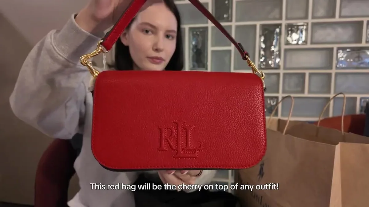 Me holding a small red Ralph Lauren flap bag with an embossed monogram and red strap.