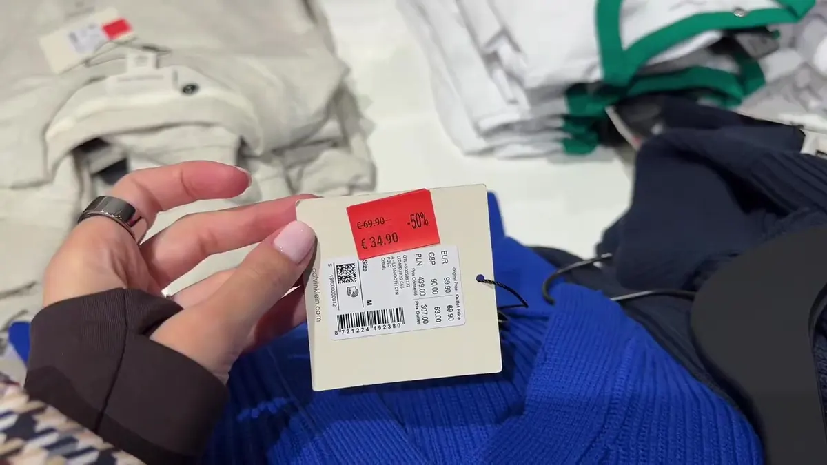 Bright blue Calvin Klein knit and a label showing original €99.90, outlet €69.90 and sale €34.90.