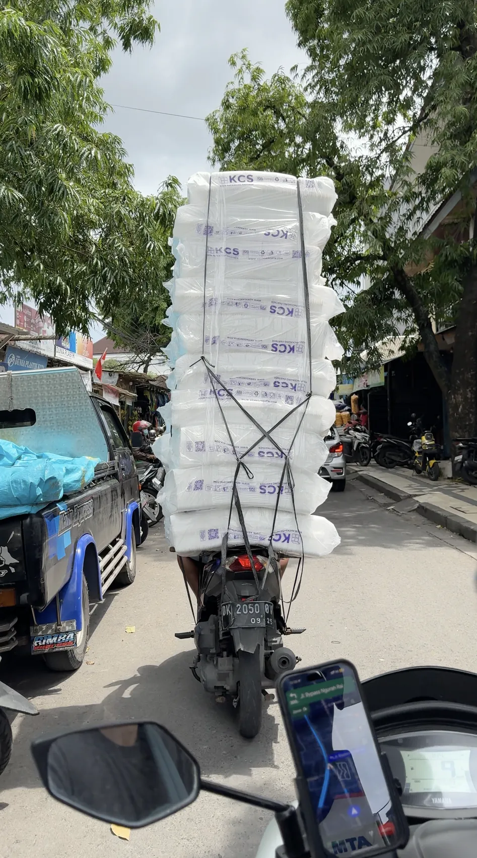 A scooter carrying a tall stack of white boxes on a busy street