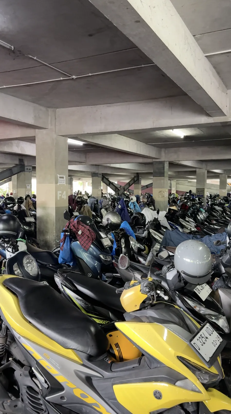 Rows of scooters parked under a concrete roof