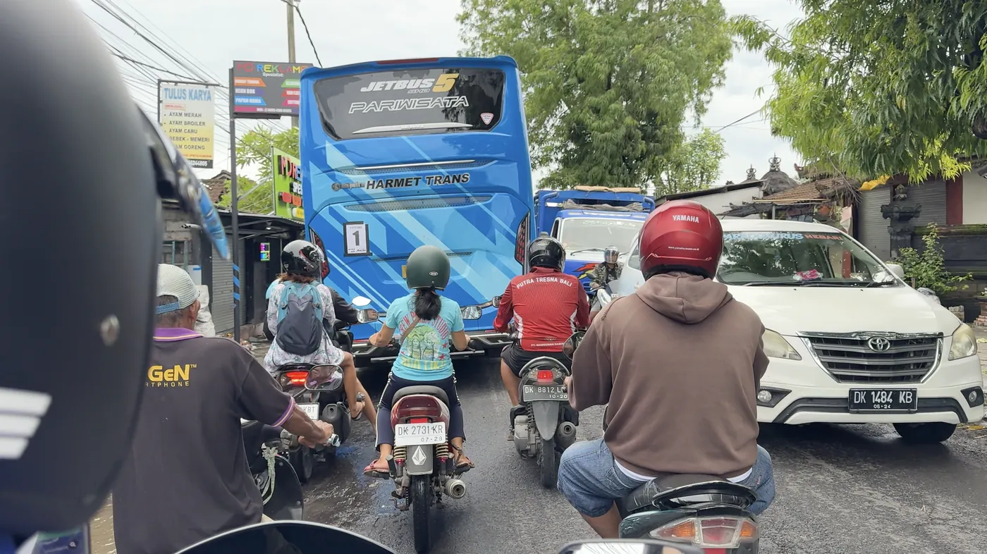 A busy road with a blue bus, a car and many scooters ahead