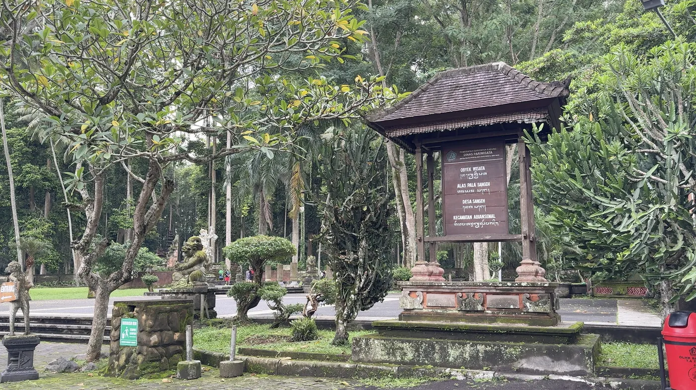 A small wooden pavilion with an information board among frangipani trees