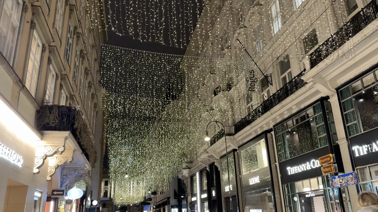 Curtains of warm white lights hanging over a narrow shopping street in the city centre.