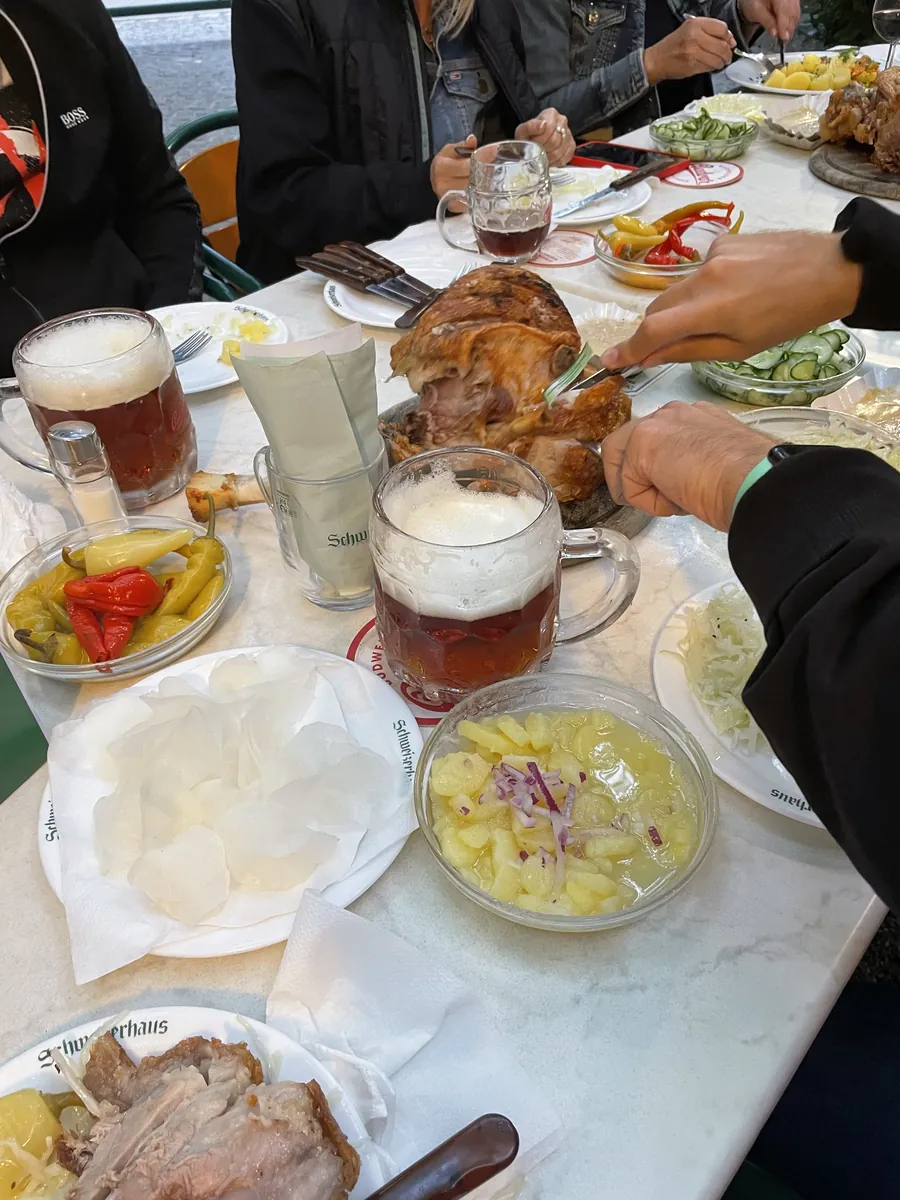 Roast pork being carved at a Schweizerhaus table with beer and salads