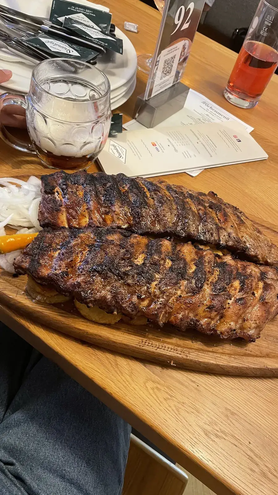 Grilled ribs on a wooden board beside a beer mug at Strandcafé